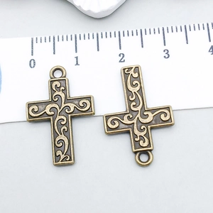 Macro detail of bronze alloy hollow cross pendants with vintage scroll patterns and a ruler
