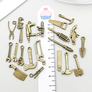 Detailed macro view of bronze-finished miniature alloy tool pendants on a gray backdrop