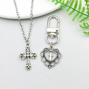 Detailed view of vintage silver alloy hollow cross pendant necklace and heart-frame keychain