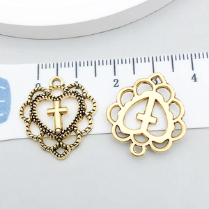 Detail of vintage gold heart cross pendants with 25mm measurement scale on neutral background