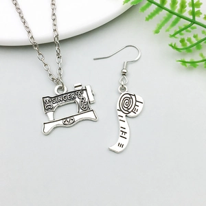 Detail van de antiek zilveren naaimachine ketting en meetlint oorbellen met SINGER gravering