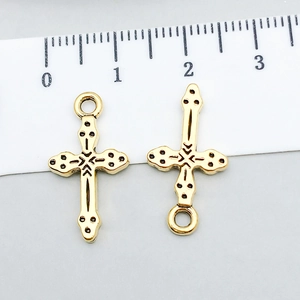Macro view of two antique gold cross pendants with vintage texture and size ruler