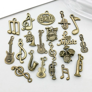 Dettaglio di ciondoli musicali in bronzo antico con chitarre e note per gioielli DIY