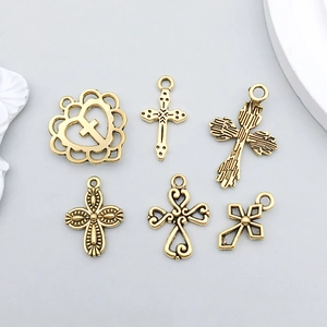 Detail view of six antique gold alloy cross and heart charms for DIY jewelry making