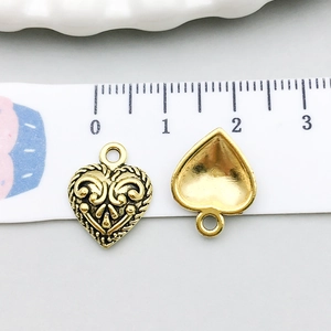 Vue macro d'un pendentif cœur en or antique avec reliefs et dimensions sur une règle