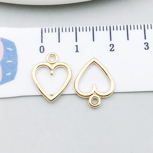 Close-up of 10mm hollow heart-shaped alloy pendant charms with ruler for size reference