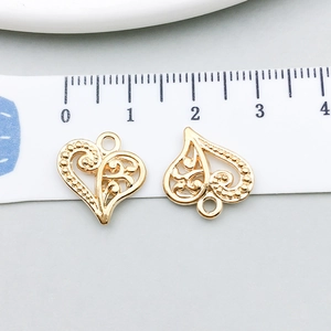 Macro shot of gold hollow heart charms with scrollwork and scale measurement