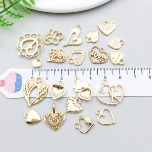 Golden heart pendants with wings and engravings shown with a ruler for size reference