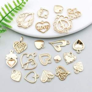 Collection of gold heart-shaped alloy pendants with wings and engravings on ceramic plate
