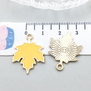 Macro detail of yellow enamel maple leaf charms with size measurements for DIY jewelry