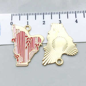 Vue détaillée du pendentif harpe en émail rose avec placage d'or et règle pour comparaison