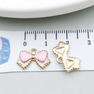 Detailed size view of pink enamel bow charms and gold alloy pendants for DIY jewelry