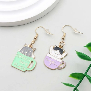 Detail of cute cat coffee cup drop oil earrings in pastel purple and mint green colors