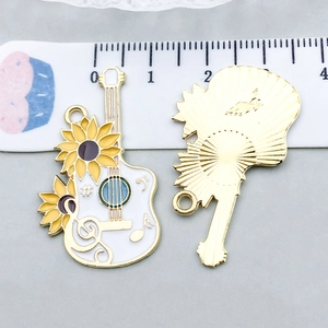 Détail macro de breloques violoncelle en émail avec tournesols et règle de mesure