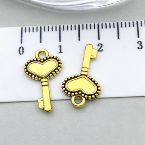 Detail of vintage gold heart-shaped key charms showing size dimensions on a ruler