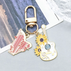 Détail de pendentifs musicaux en alliage doré avec breloques guitare et harpe émaillées