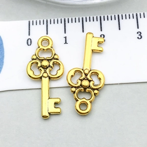 Detail view of two antique gold alloy heart key charms with size ruler reference