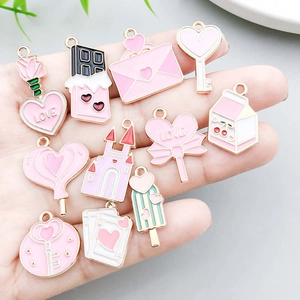 Hand holding pink enamel alloy charms set including heart and rose for DIY jewelry making