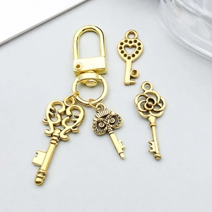 Close-up of golden alloy heart key charms with owl and floral filigree details