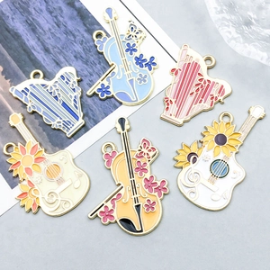 Vue détaillée de breloques en émail coloré en forme de violon harpe et guitare pour bijoux