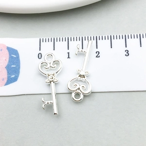 Vue détaillée de pendentifs clé cœur argentés avec ruban à mesurer pour la taille