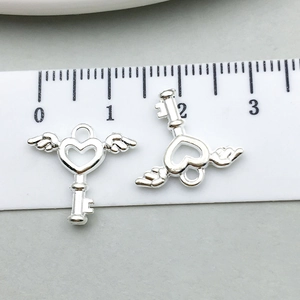 Vue macro de pendentifs clé cœur ailé en argent avec échelle de mesure pour bijoux DIY