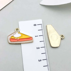 Detailed scale view of a 2.5cm yellow cake slice charm with colorful enamel and gold back