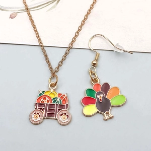 Detail of harvest cart necklace and turkey earring with Thanksgiving enamel charms
