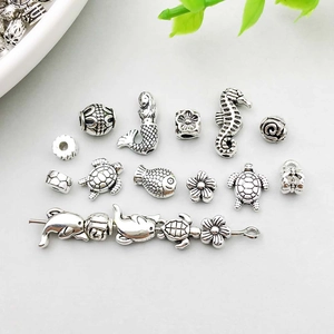 Macro detail of ocean-themed silver charms including mermaid, seahorse and sea turtle