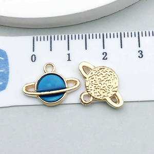 Vue macro de breloques planète en émail bleu avec texture dorée et règle de mesure
