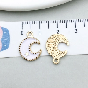 Detail view of crescent moon pendants with white enamel and golden star measured by ruler