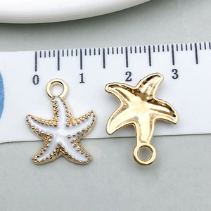 Detailed macro of enamel white starfish pendants with gold plating and size scale