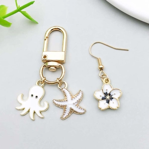 Detail view of white enamel octopus, starfish charms and flower earrings in gold finish