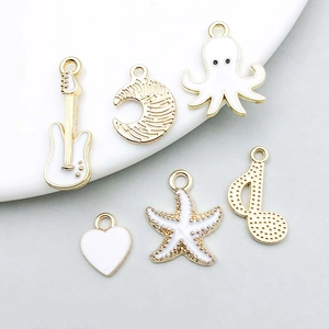 Detail of white enamel and gold alloy charms including starfish, heart, and moon shapes