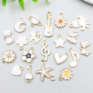 Selection of white enamel and gold alloy charms featuring daisies, stars and butterflies