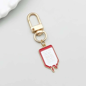 Macro view of medical blood bag charm pendant with red enamel and gold lobster clasp