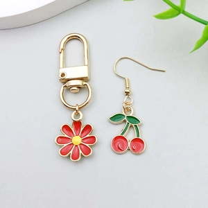 Detail of red cherry oil drip earrings and yellow daisy keychain with gold lobster clasp