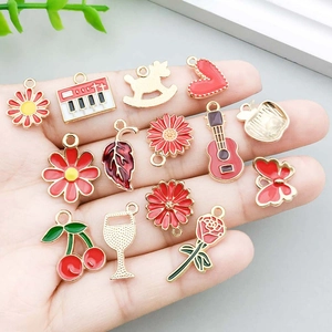 Assorted red enamel alloy floral charms for DIY jewelry making displayed on a hand