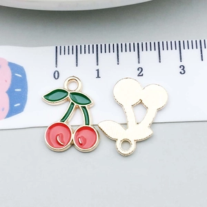 Detail of red cherry charms with green leaves showing front enamel and gold metal back