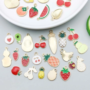 Flat lay of colorful enamel fruit charms including cherry and avocado for DIY jewelry