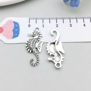 Detail of vintage silver seahorse charms showing texture and size with a measuring ruler