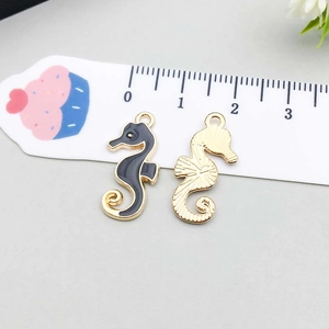 Detail view of colorful seahorse alloy charms with enamel finish next to a scale ruler
