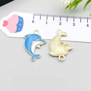 Detail of blue and white enamel dolphin pendants with gold metal back for DIY jewelry