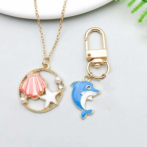 Detailed view of marine animal jewelry set with enamel shell necklace and dolphin keychain