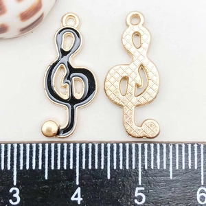 Macro shot of treble clef music charms in black enamel and gold finish with dimensions