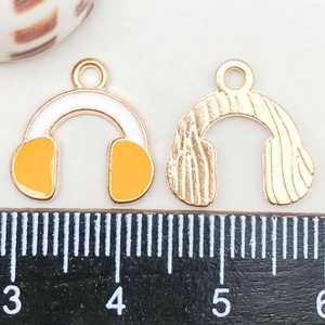 Macro detail of a 20mm golden headphone charm with white and yellow enamel inlay