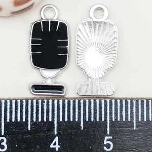 Detail of vintage microphone alloy charm with black oil drip and size reference