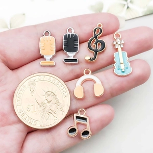 Music themed colorful enamel charms including microphone and guitar next to a coin