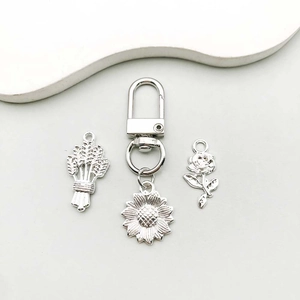 Detail view of silver sunflower, rose, and wheat ear pendants with lobster clasps