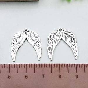 Macro detail of antique silver wing pendant showing feather texture and size scale